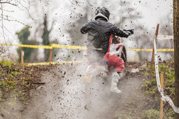 pilota irriconoscibile che guida una moto da enduro in fuoristrada su un terreno fangoso, visto di spalle