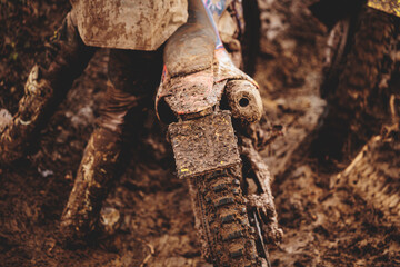 dettagli di una persona irriconoscibile che cerca di guidare una moto da fuoristrada fuori da un terreno fangoso