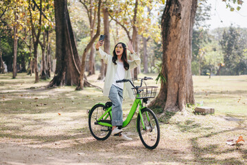 Fototapeta premium A woman is riding a green bicycle in a park