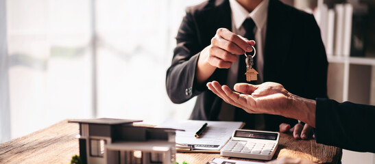A man in a suit is handing a key to a woman