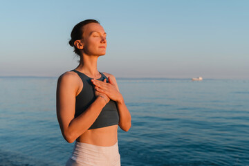 Woman meditating and breathing at seaside at sunset or sunrise. Holistic Health and Mental Well-Being.