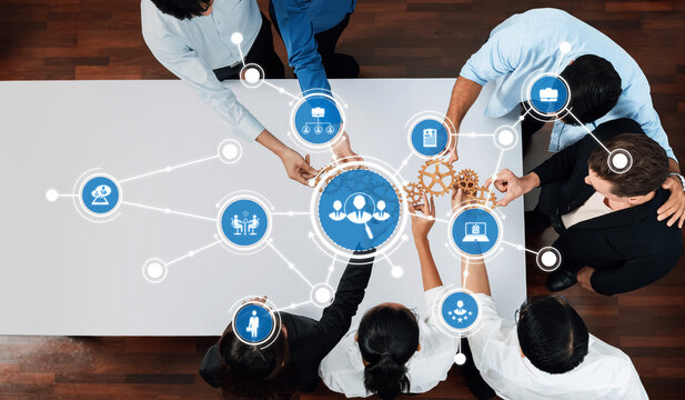 A diverse team engages in collaboration while surrounded by technology icons and gears, symbolizing innovation and strategic teamwork in a modern work environment. Amity