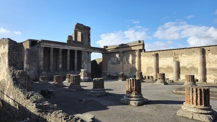 Pompeii, Italy - 8 January 2025. The basilica's ruins include brick column remains, tall fluted columns, and a central elevated hall framed by stone structures and open sky.