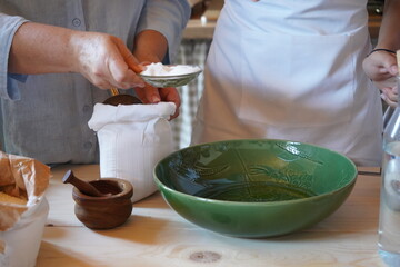 Traditional Greek cooking scene in Crete. A young man and a boy prepare ingredients with a green...