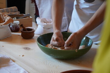 A child’s hands kneading dough in a green ceramic bowl during a traditional Cretan cooking workshop. The preparation of 