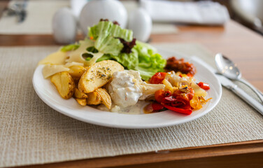 Plate with salad, roasted vegetables, potatoes, and cheese on dining table. Healthy lunch option, balanced nutrition, and hotel meal concept.