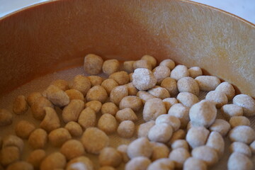 Close up of a round wooden sieve which contains small, round dough balls, the 