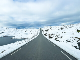 A winter landscape along the Sognefjellsvegen road in Norway, featuring snow-covered mountains and a vast, serene terrain.