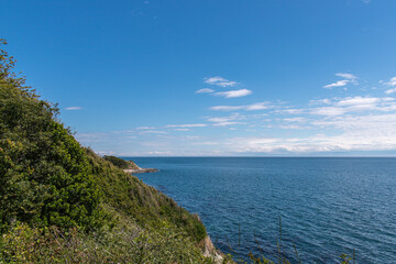 Scenic view of the Pacific Ocean from a verdant cliffside near Clover Point in Victoria BC, Canada, on a clear summer day.