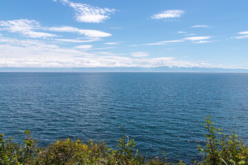 Clear summer day overlooking the calm, sparkling blue Pacific Ocean from a grassy bluff near Clover Point in Victoria, British Columbia, Canada.