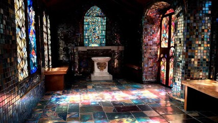 Colorful light streams through stained glass windows, illuminating the mosaic interior of a small chapel, creating a serene and spiritual atmosphere - Powered by Adobe