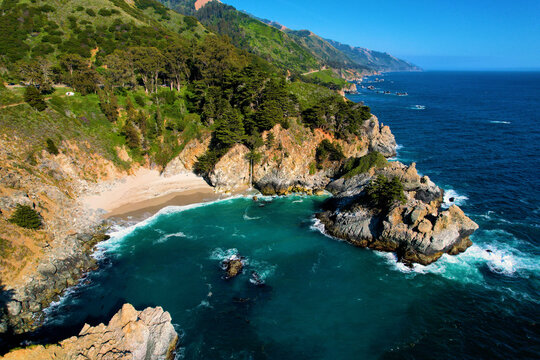 Aerial view of world famous McWay Falls at Sunset. Rare sight a waterfall that flows directly in the ocean. West Coast Big Sur USA. Pacific Ocean. Clear blue water with cliffs at golden hour