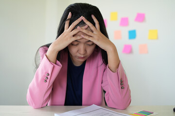 Tired and unhappy female manager is working at office with paper documents and feeling headache....