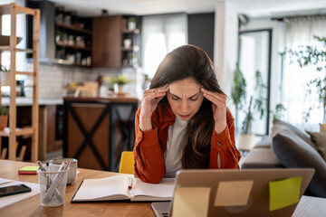 Stressed freelancer woman suffering from headache while working at home