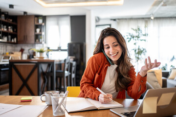 Freelancer working from home having phone call and taking notes