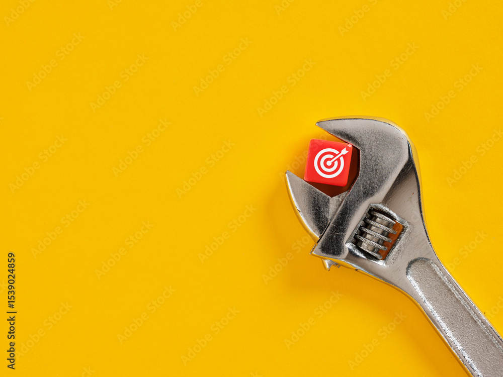 Poster adjustable wrench holding red cube with target symbol on yellow background