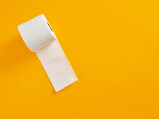 White toilet paper roll unraveling on vibrant yellow background