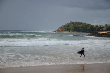 Sydney, New Sowth Wales, Australia. May 21, 2013: Surfer walking along the shore at a Sydney beach...