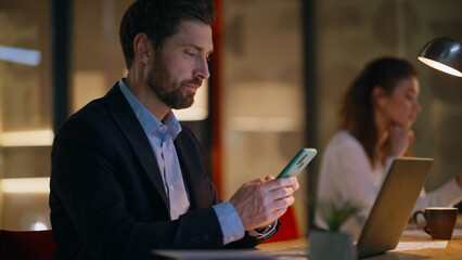 Office team browsing cellphones at evening office coworking space closeup.