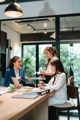 Office mentor with guidance from supervisor coaching a new intern on daily business tasks in Asian workplace