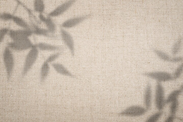 Natural, minimalist background. Texture of beige linen fabric with soft shadows from leaves.