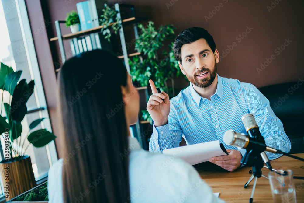 Poster two professionals collaborating in a modern workspace during an interview or work discussion at the 