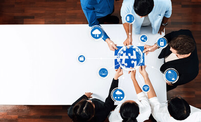 A diverse group of professionals collaborates on a technology puzzle, surrounded by digital icons symbolizing cloud, security, and connectivity, fostering teamwork in a modern office setting. Amity