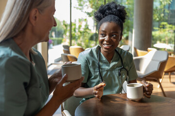 Two female doctors having coffee and discussing something