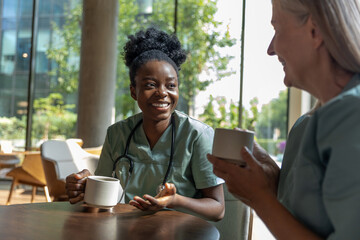 Two female doctors having coffee and discussing something