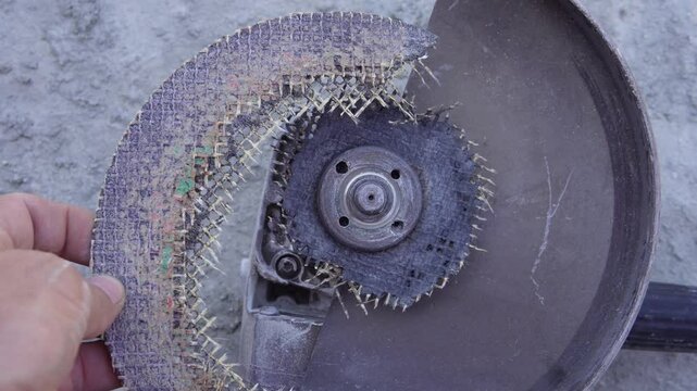 A damaged angle grinder disc. Part of the disc has broken off, revealing the worn and frayed fiberglass mesh inside. Only the part attached to the grinder remains.