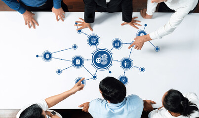 A diverse business team collaborates to analyze key performance indicators on a table, utilizing technology icons that emphasize data-driven insights and strategies. Amity