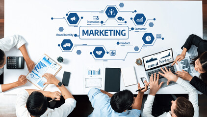 A diverse team engaged in a marketing strategy meeting, utilizing digital devices to analyze data visuals. The modern office environment fosters collaboration and creativity. Amity