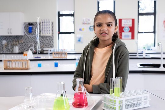Girl in school science lab with colorful beakers, exploring chemistry experiments