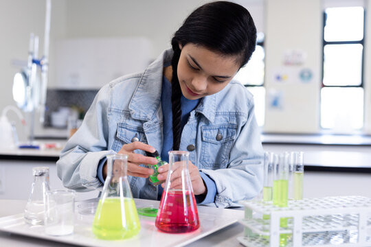 Girl conducting science experiment with colorful liquids in school laboratory