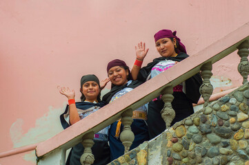 Indigenous girls waving from staircase in traditional clothing