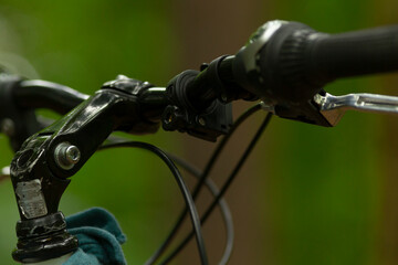 The handlebars of a bicycle prominently display the gear shifter, brake lever, and cables,...