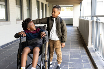 Diverse boys supporting each other in school hallway, smiling and enjoying friendship