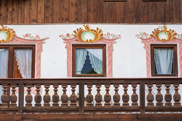 Charming alpine buildings in Mittenwald feature colorful Lüftlmalerei (frescoes), wooden balconies, and flower-filled window boxes, all set against a dramatic mountain backdrop.