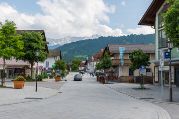 Charming alpine buildings in Mittenwald feature colorful Lüftlmalerei (frescoes), wooden balconies, and flower-filled window boxes, all set against a dramatic mountain backdrop. © Andrei Tomas