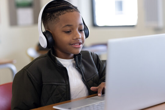 In school, young boy using laptop and headphones, engaged in learning