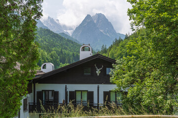 Charming alpine buildings in Mittenwald feature colorful Lüftlmalerei (frescoes), wooden balconies, and flower-filled window boxes, all set against a dramatic mountain backdrop.