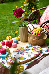 Close-up of a small garden table with embroidery supplies on a warm summer day. Colorful threads, needles, fabric, scissors, and a wooden hoop are neatly arranged in natural light. The table stands in