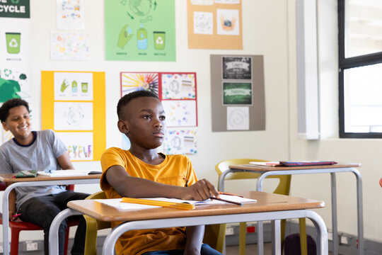 In school, diverse students listening attentively in classroom with colorful posters around