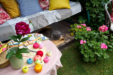 A cozy summer garden scene featuring a cushioned swing used as a relaxing embroidery spot, with a...