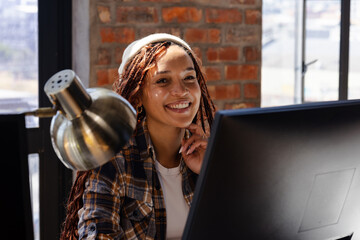 woman coding on computer, smiling in modern office