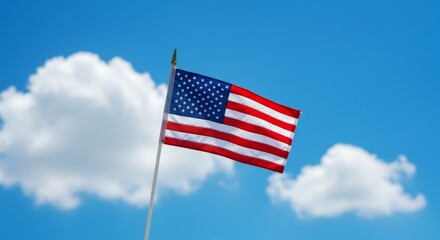 Obraz premium American flag waving against a clear blue sky with clouds 