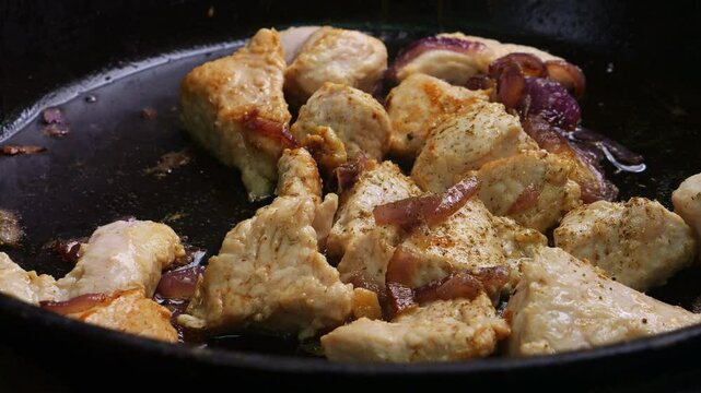 Chicken pieces fried in sauce and spices in a frying pan. Medium shot.
