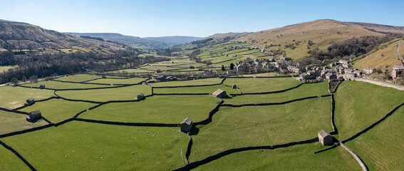 Aerial panorama of traditional stone barns in fields at Gunnerside in Swaledale in the Yorkshire Dales UK