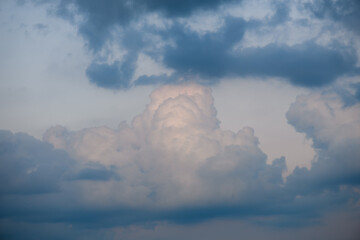 Dramatic cloud formations create an atmospheric scene during twilight near a serene landscape in...