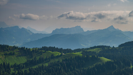 Dramatic mountain landscape with rolling hills and distant peaks under a cloudy sky in a tranquil...
